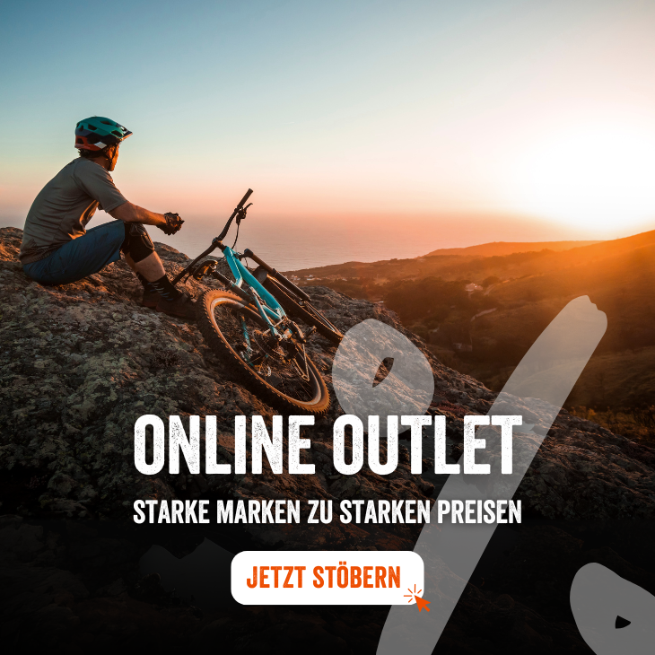 Mountainbiker sitzt bei Sonnenuntergang auf einem Felsen mit Blick aufs Meer, daneben ein Fahrrad – Werbebanner für ein Online Outlet mit dem Text ‚Starke Marken zu starken Preisen‘ und einem Button ‚Jetzt stöbern‘